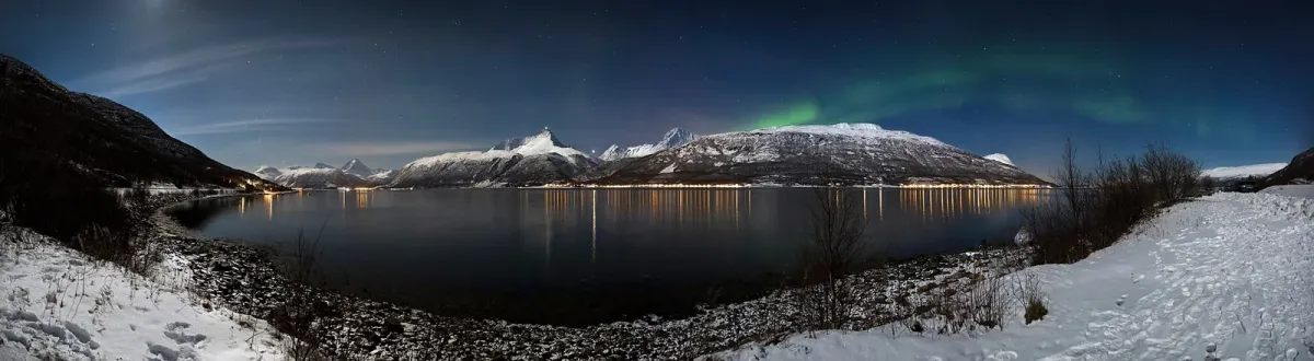 The Lyngen Alps across Storfjorden on a winter night, the mountains behind husky dog sledding from Tromsø